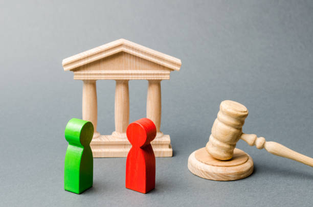 ÁREA DE ATENCIÓN E INTERVENCIÓN JURÍDICA Wooden figures of people standing near the judge's gavel. Litigation. Business rivals. Conflict of interest. Law and justice. The layer's services. Two opponents. Judgment. Gavel. Red and green