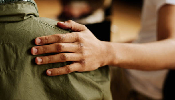 ÁREA SOCIAL Y-O ECONÓMICA Hand of young supportive man consoling his friend or one of attendants with post traumatic syndrome caused by dramatic life event